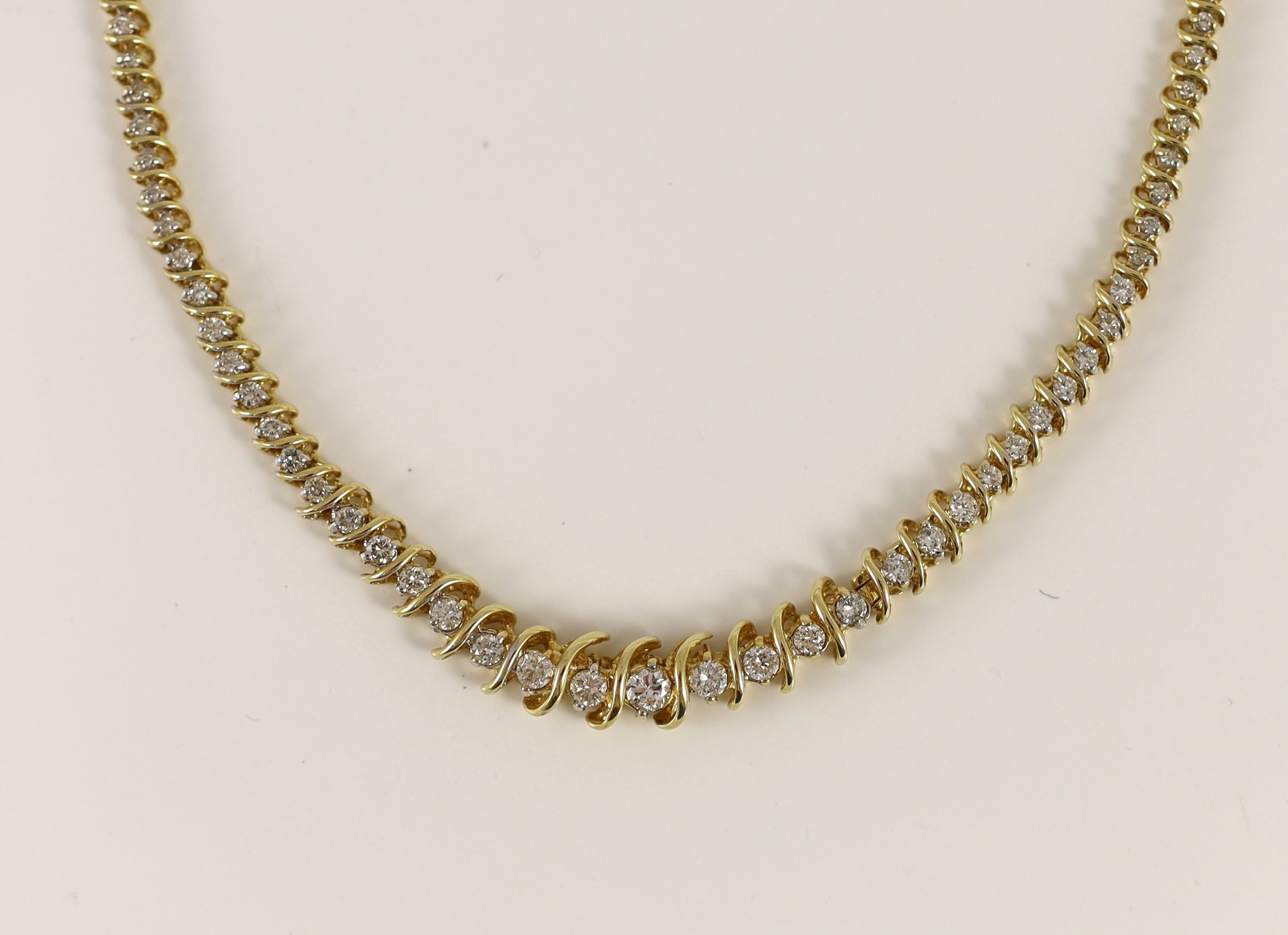 A modern 14k gold and graduated diamond set shaped line necklace